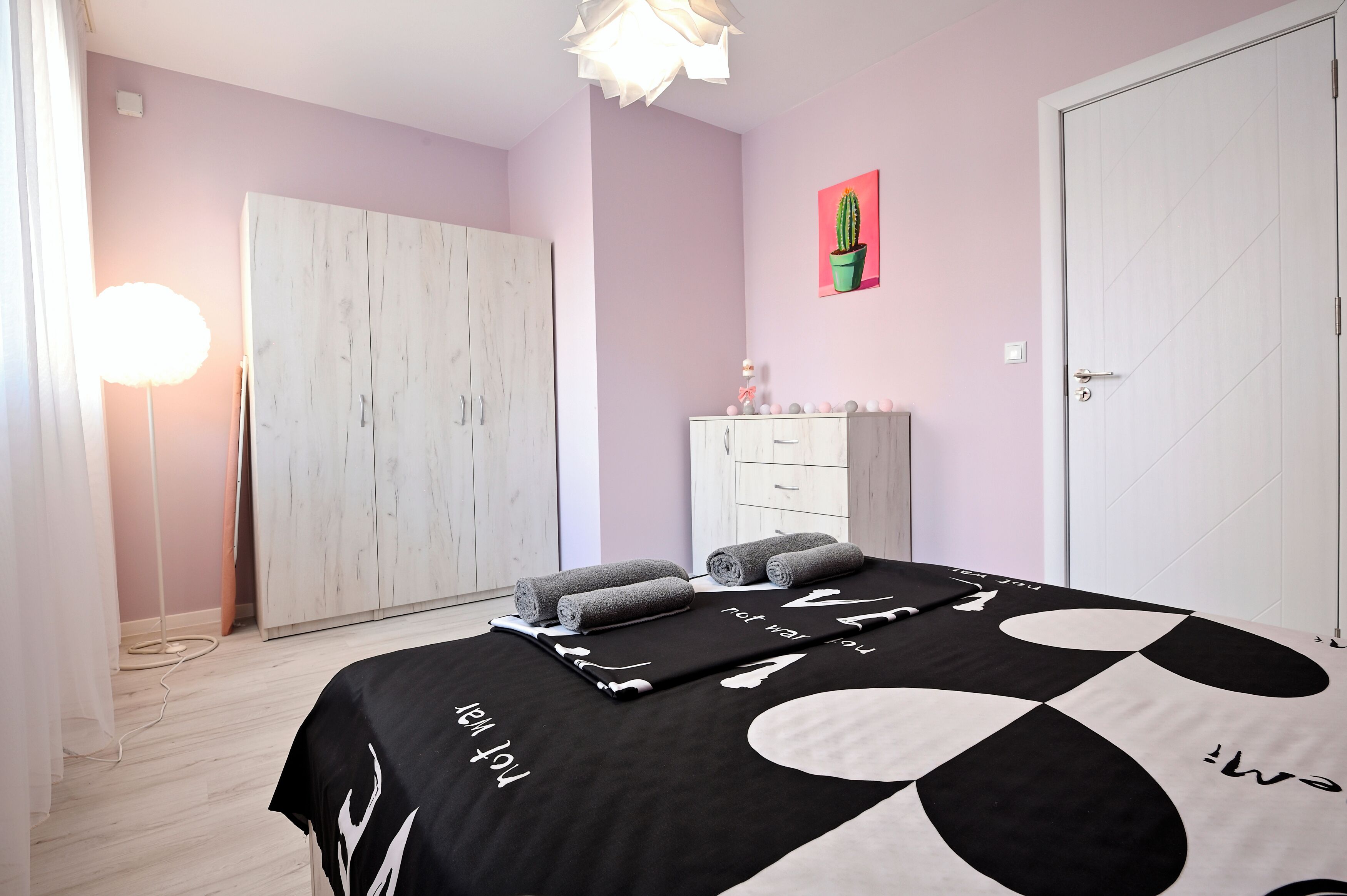 Ein Schlafzimmer mit Bett, Kleiderschrank, Kommode und einem Bild an der Wand.
