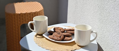 A small round table with a white plate of cookies and two white mugs.