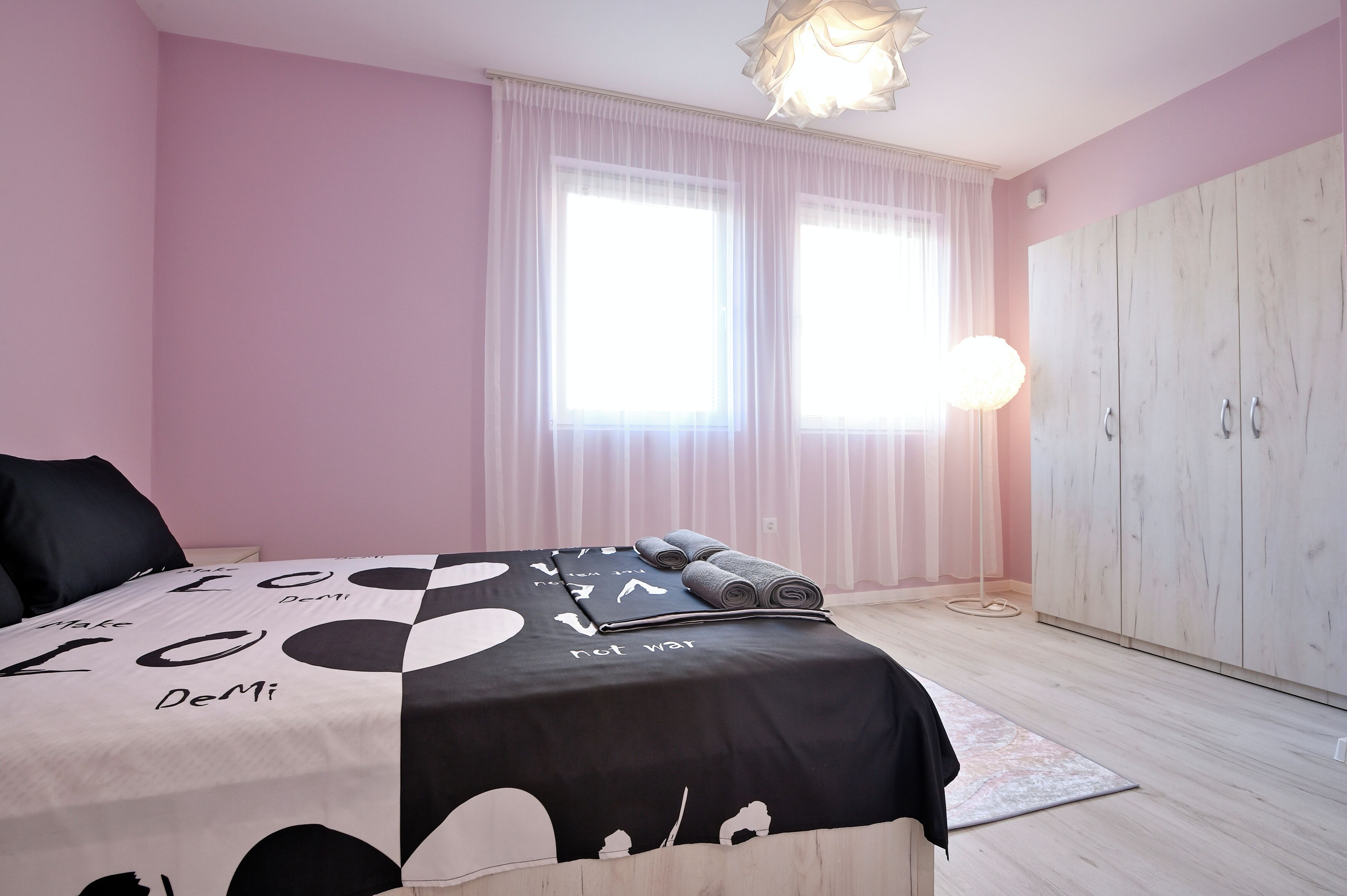 Une chambre à coucher avec un lit, une armoire et une fenêtre avec des rideaux.