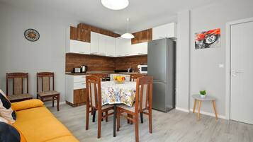 A compact kitchen with modern appliances, wooden cabinets, and a dining area with a floral tablecloth.