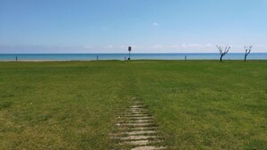 En gräsbevuxen äng med klar himmel och en avlägsen utsikt över havet.
