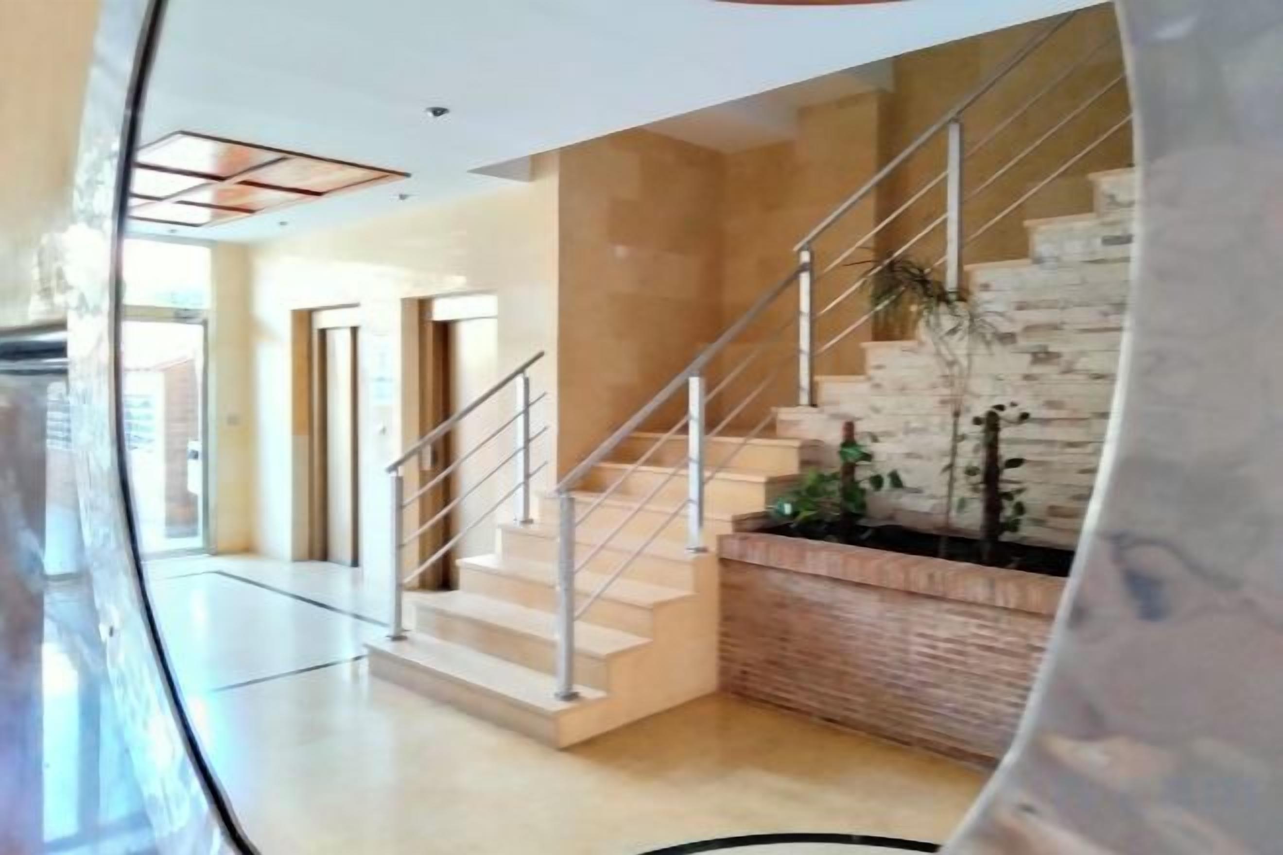 Un interior moderno con una escalera, un banco de madera y vistas al exterior.