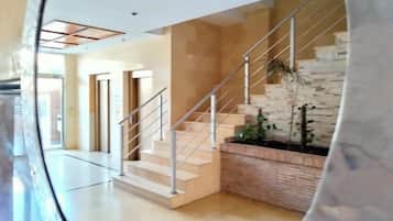 Un interior moderno con una escalera, un banco de madera y vistas al exterior.
