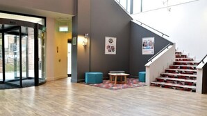 A lobby with a staircase, a glass door entrance, and a small seating area with a patterned rug. - Holiday Inn GLASGOW - EAST KILBRIDE by IHG (East Kilbride)