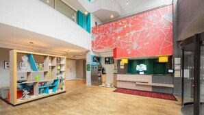 A hotel lobby with a reception desk, a children's play area, and a staircase leading to an upper level. - Holiday Inn GLASGOW - EAST KILBRIDE by IHG (East Kilbride)