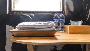 A wooden table with a folded white towel, two Summit water bottles, and a tissue box. - Exotic Inn Semarang, by INNCA COLLECTION (Semarang)