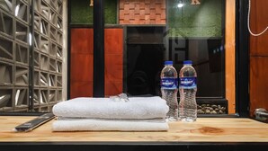 A wooden counter with a folded white towel, two Summit water bottles, and a smartphone. - Exotic Inn Semarang, by INNCA COLLECTION (Semarang)