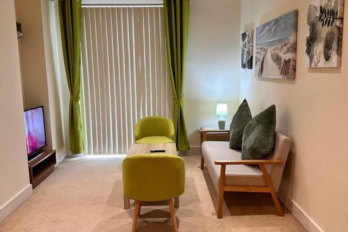 A living room with a sofa, a chair, a TV, a lamp, and artwork on the wall.