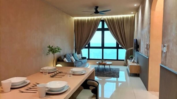 A modern dining area with a long table set for four, a ceiling fan, and a view of the sea through large windows. - L23-ParadigmMall Residence Skudai JB 3R2B-10pax (Tebrau)