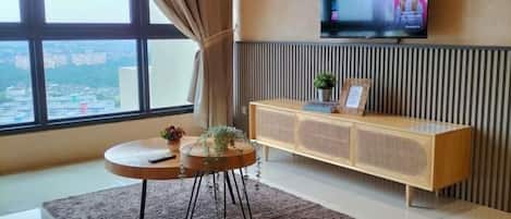 Un salon moderne doté d’une grande fenêtre, d’un téléviseur à écran plat, d’une table basse ronde et d’une console en bois.