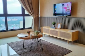 A modern living room with a large window, a flat-screen TV, a round coffee table, and a wooden console table. - L23-ParadigmMall Residence Skudai JB 3R2B-10pax (Tebrau)