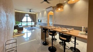 A modern dining area with a long table, bar stools, and pendant lighting. - L23-ParadigmMall Residence Skudai JB 3R2B-10pax (Tebrau)