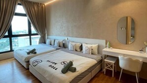 A hotel room with two beds, a desk, a chair, a mirror, and a view of the city through large windows. - L23-ParadigmMall Residence Skudai JB 3R2B-10pax (Tebrau)