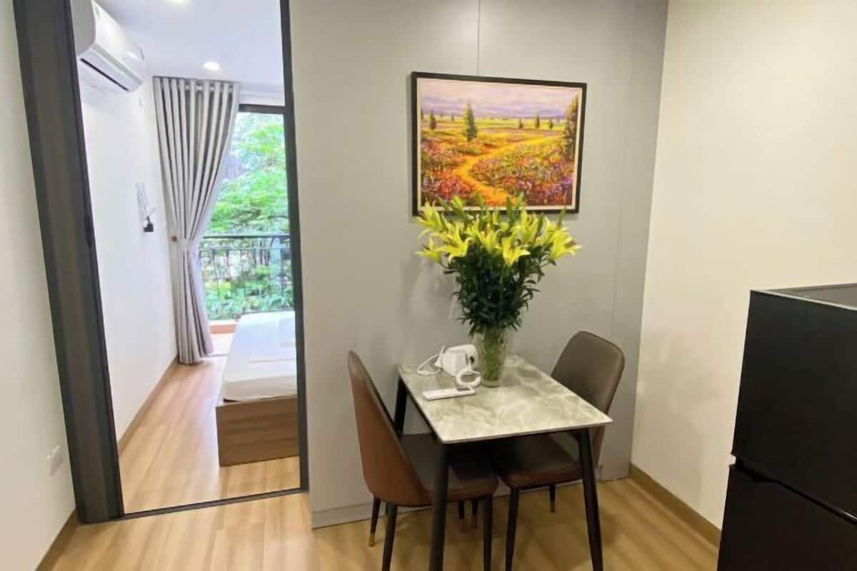 Une pièce comprenant une table à manger, des chaises, une plante en pot, un tableau et un réfrigérateur noir.