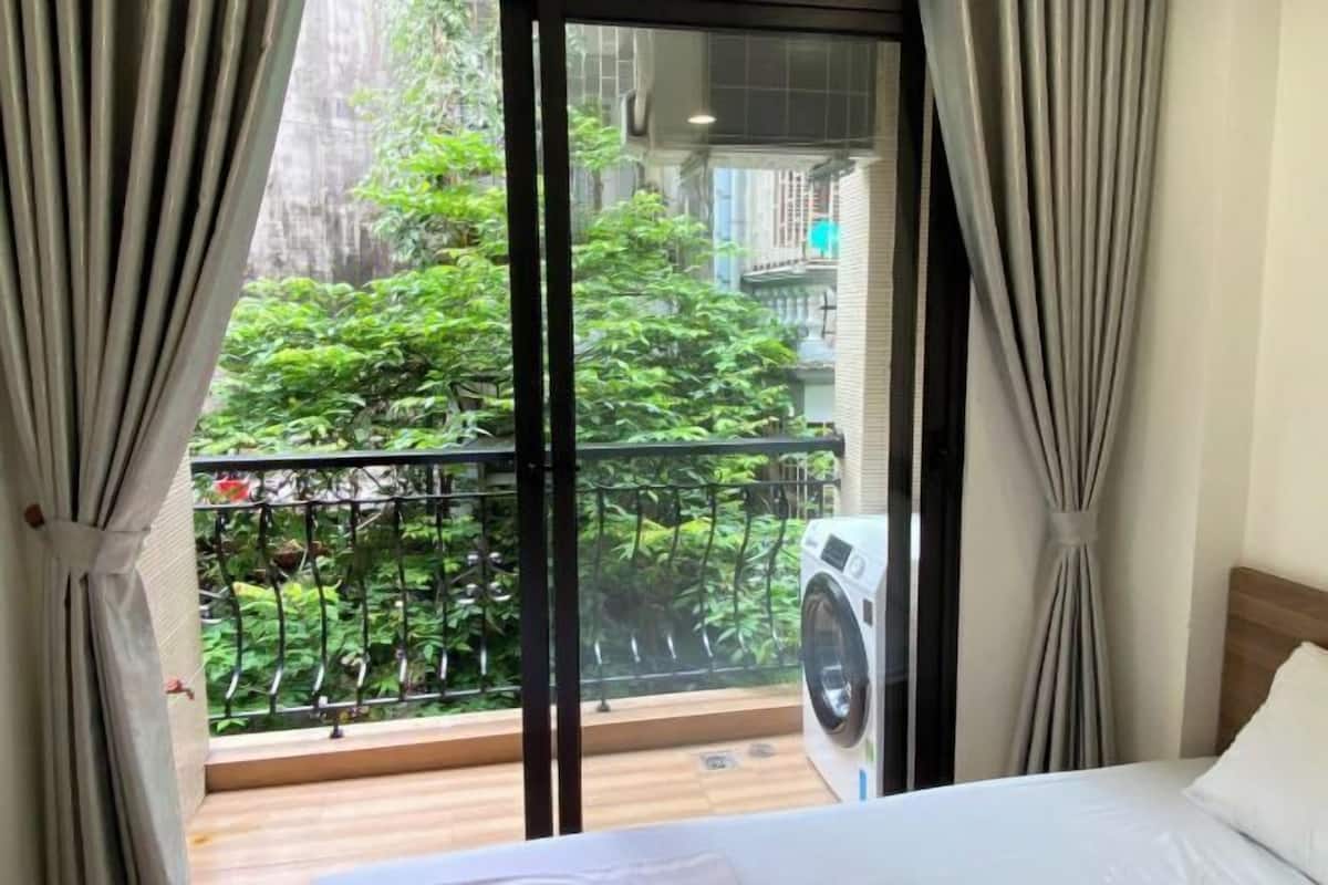 Une chambre d’hôtel avec une grande fenêtre, un lit et un lave-linge.