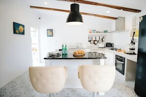 A modern kitchen with a central island, white cabinetry, and a hanging pot rack.