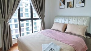 Een hotelkamer met een groot raam, een bed met een wit hoofdeinde en drie ingelijste foto's aan de muur.