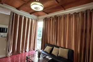 A room with a sofa, a glass coffee table, and curtains. - Brilliant SKY (Tagaytay)