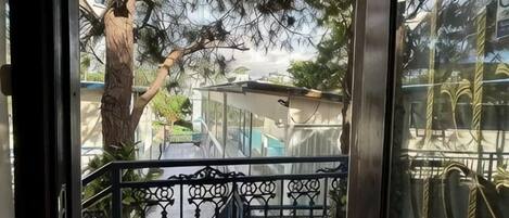A balcony with a metal railing, a tree, and a building in the background.
