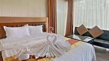 A hotel room with a large bed, a sofa, and a view of the outdoors.