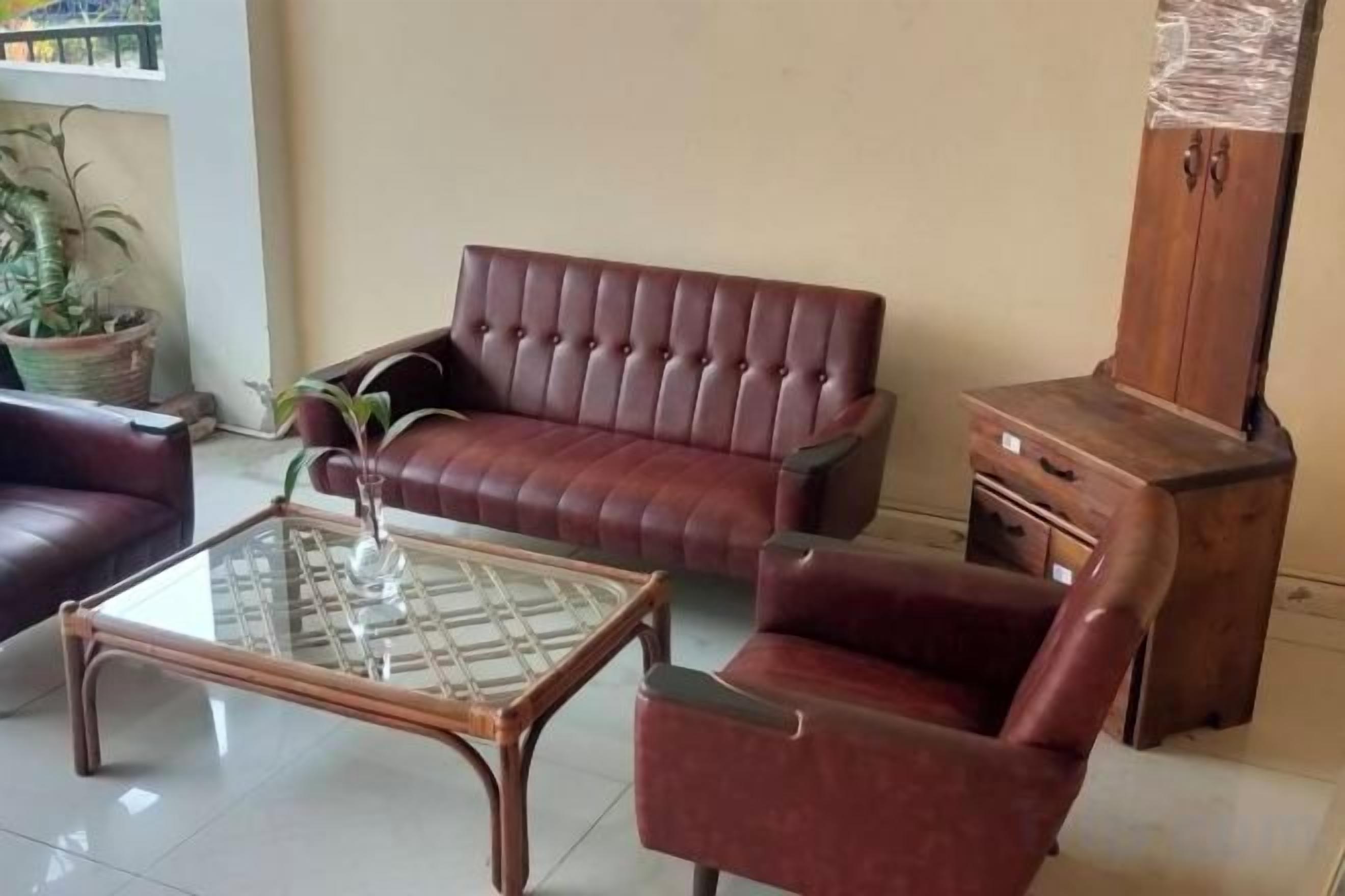 A living room with a leather sofa, a glass coffee table, and a wooden cabinet.