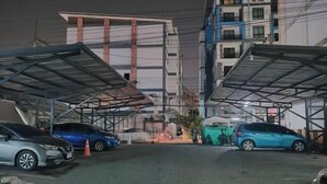 A parking area with cars and a building in the background. - Eco hostel Bangsaen (Chon Buri)