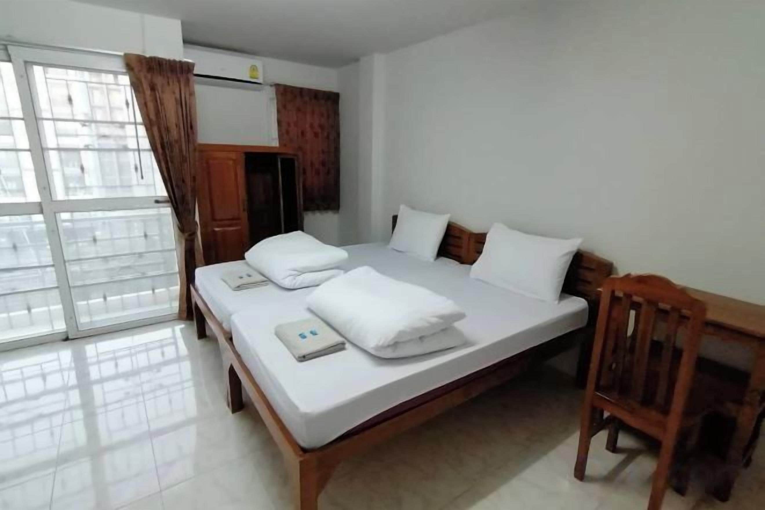 A bedroom with a bed, a wooden chair, a desk, and a wardrobe.