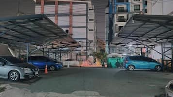 Ein Parkplatz mit Autos, einer Überdachung und einem Gebäude im Hintergrund.