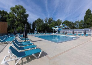 A swimming pool area with lounge chairs and umbrellas, a water slide, and a covered seating area. - Camping Domaine de la Brèche (Varennes sur Loire)
