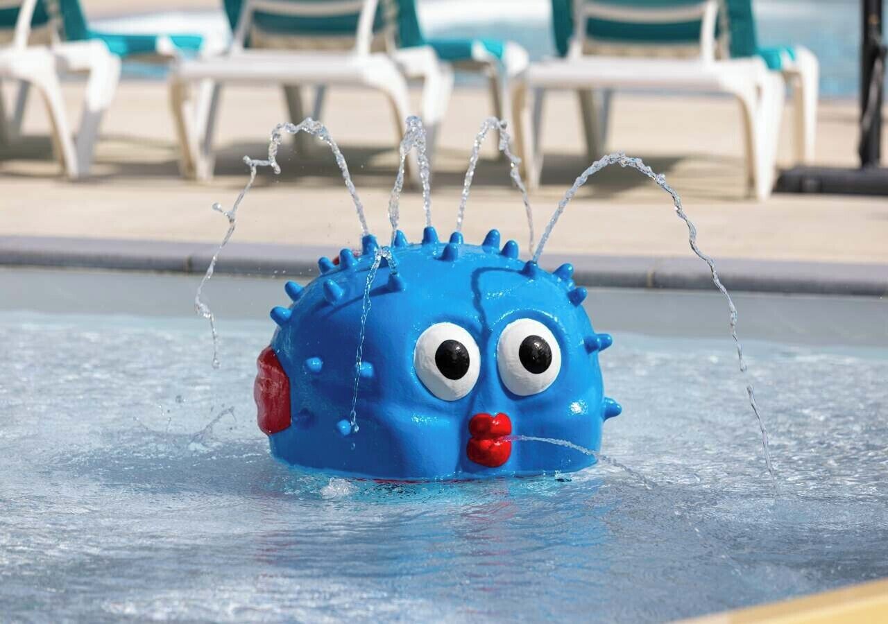 A blue water toy with googly eyes and a red mouth, splashing water in a pool.