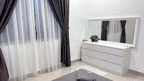 A modern bedroom with a large window, a white dresser, and a black exercise mat.