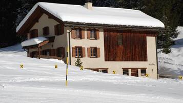 Ein Chalet mit schneebedecktem Dach, Holzläden und einem Schornstein.