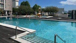 A swimming pool with a wooden deck, a water slide, and a clock tower in the background.