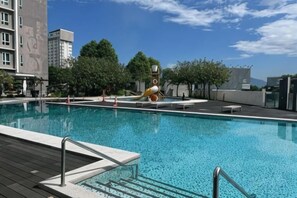 A swimming pool with a wooden deck and metal railings, surrounded by trees and buildings. - Ipoh D Festivo Suites 6-10Pax 10Mins to Sunway Tambun by Iwh (Ipoh)