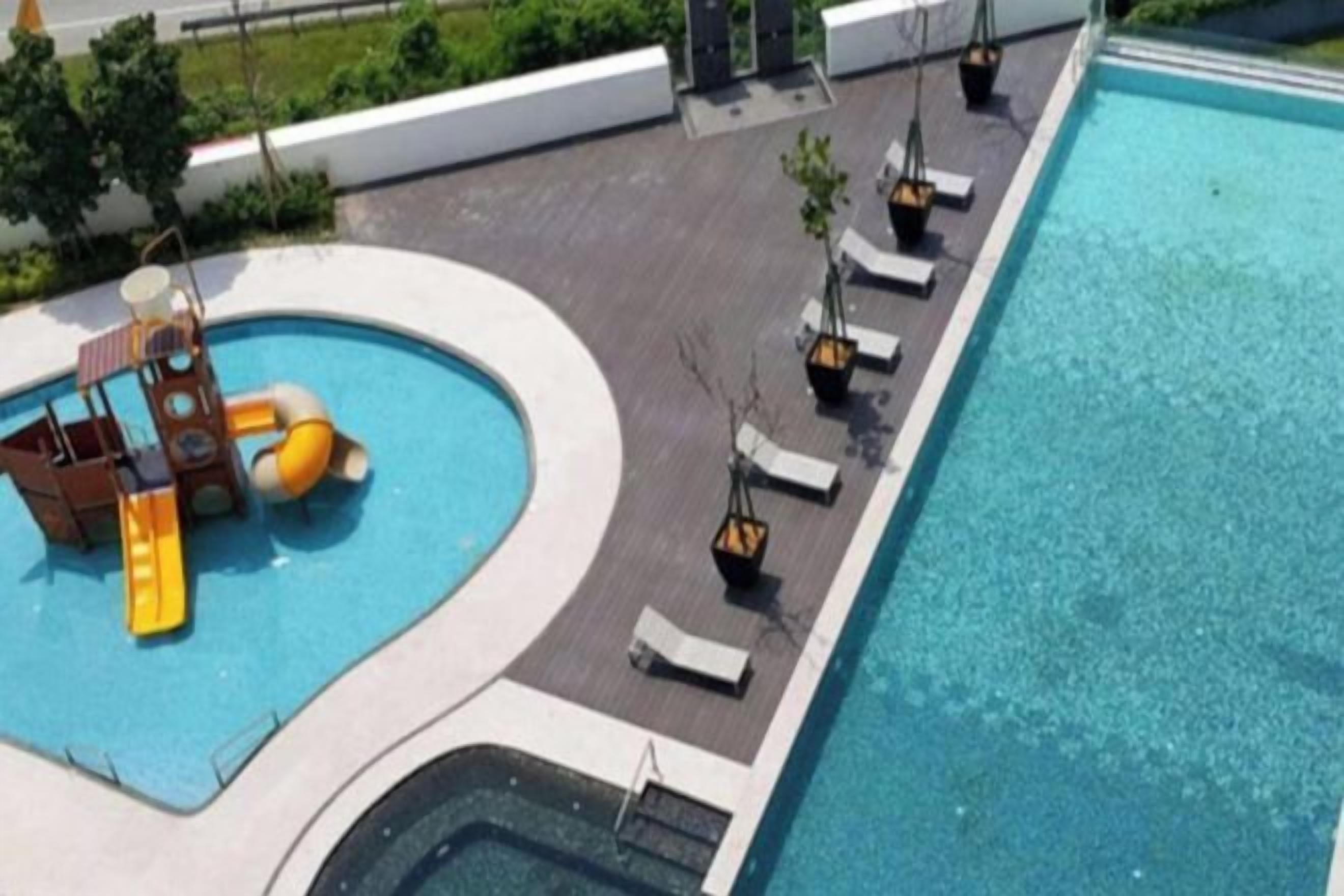 A swimming pool with a slide, lounge chairs, and a small waterfall feature.