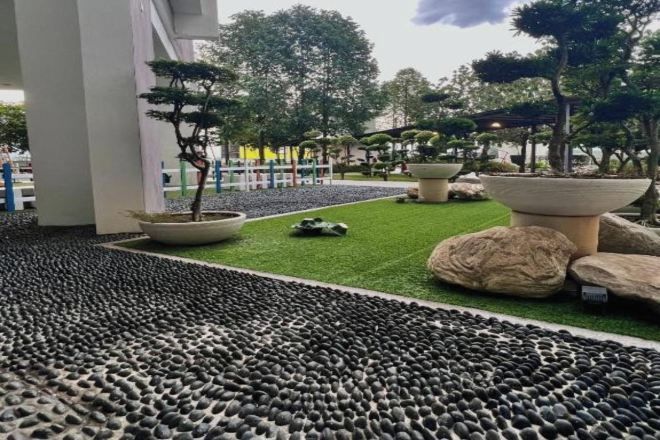 A landscaped outdoor area with artificial grass, rocks, and potted plants.