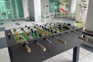 A foosball table in a lobby area with a tiled floor and a glass partition in the background. - Ipoh D Festivo Suites 6-10Pax 10Mins to Sunway Tambun by Iwh (Ipoh)