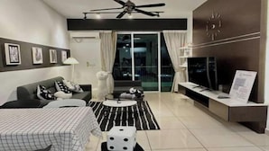 A modern living room with a sofa, a dining table, a TV, and a decorative dice on a stool.