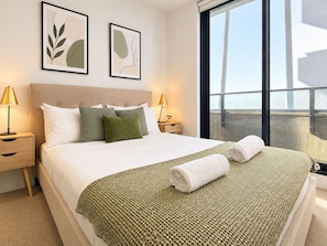 A hotel room with a bed, two bedside tables, a window, and two framed artworks on the wall.