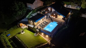 Una propiedad residencial con piscina, mobiliario exterior y un patio bien iluminado.