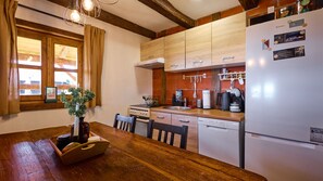 Una cocina con armarios de madera, un refrigerador, una estufa y una mesa de comedor con sillas.