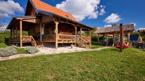 A wooden cabin with a red roof, a porch, and a small garden area. - Holiday Home Gaborcina by Villas Guide (Popovaca)