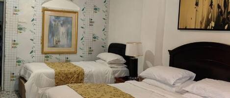 A hotel room with two beds, a nightstand, a lamp, and a painting on the wall.