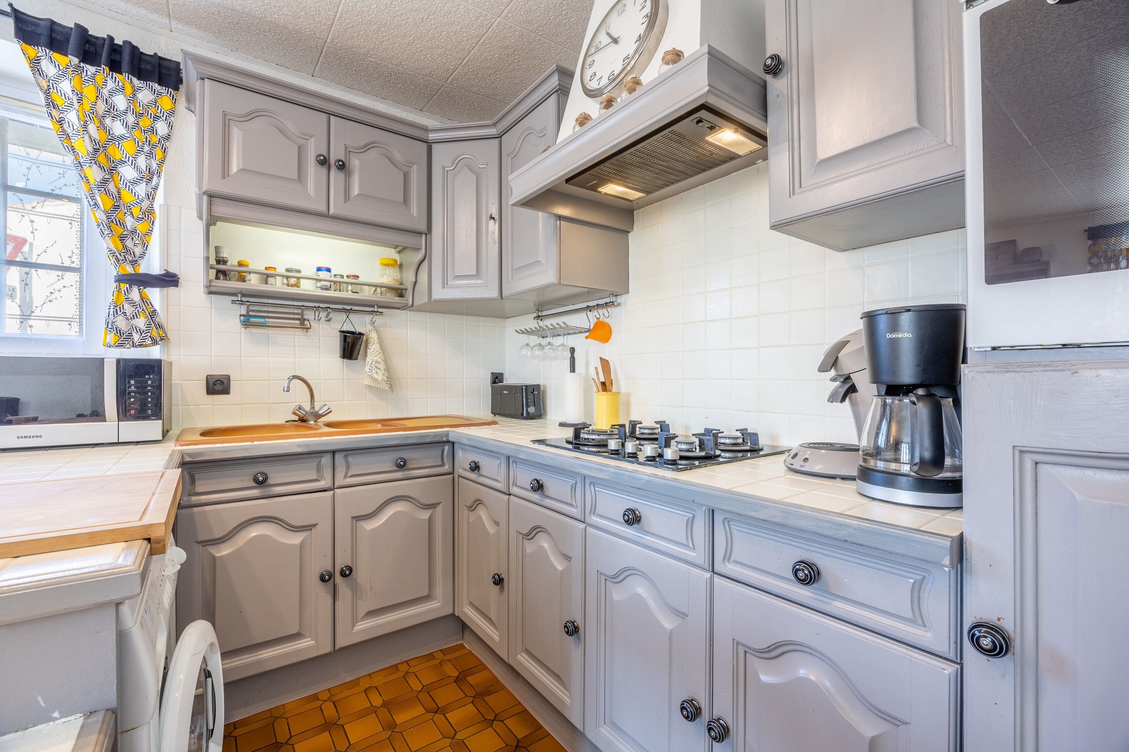 A kitchen with white cabinets, a microwave, a sink, and a coffee maker.