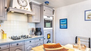 Une cuisine avec une horloge, une cuisinière, un four, une machine à café et un tableau accroché au mur.