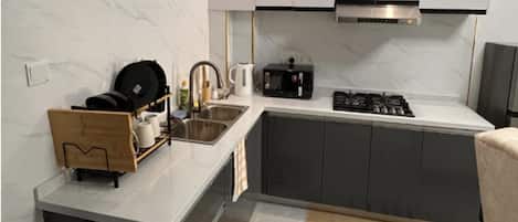 A modern kitchen with a marble backsplash, stainless steel appliances, and a wooden utensil holder.