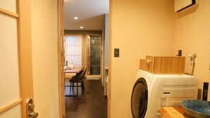 Ein Waschbereich mit Waschmaschine, einem Holzschrank und einem Essbereich im Hintergrund.