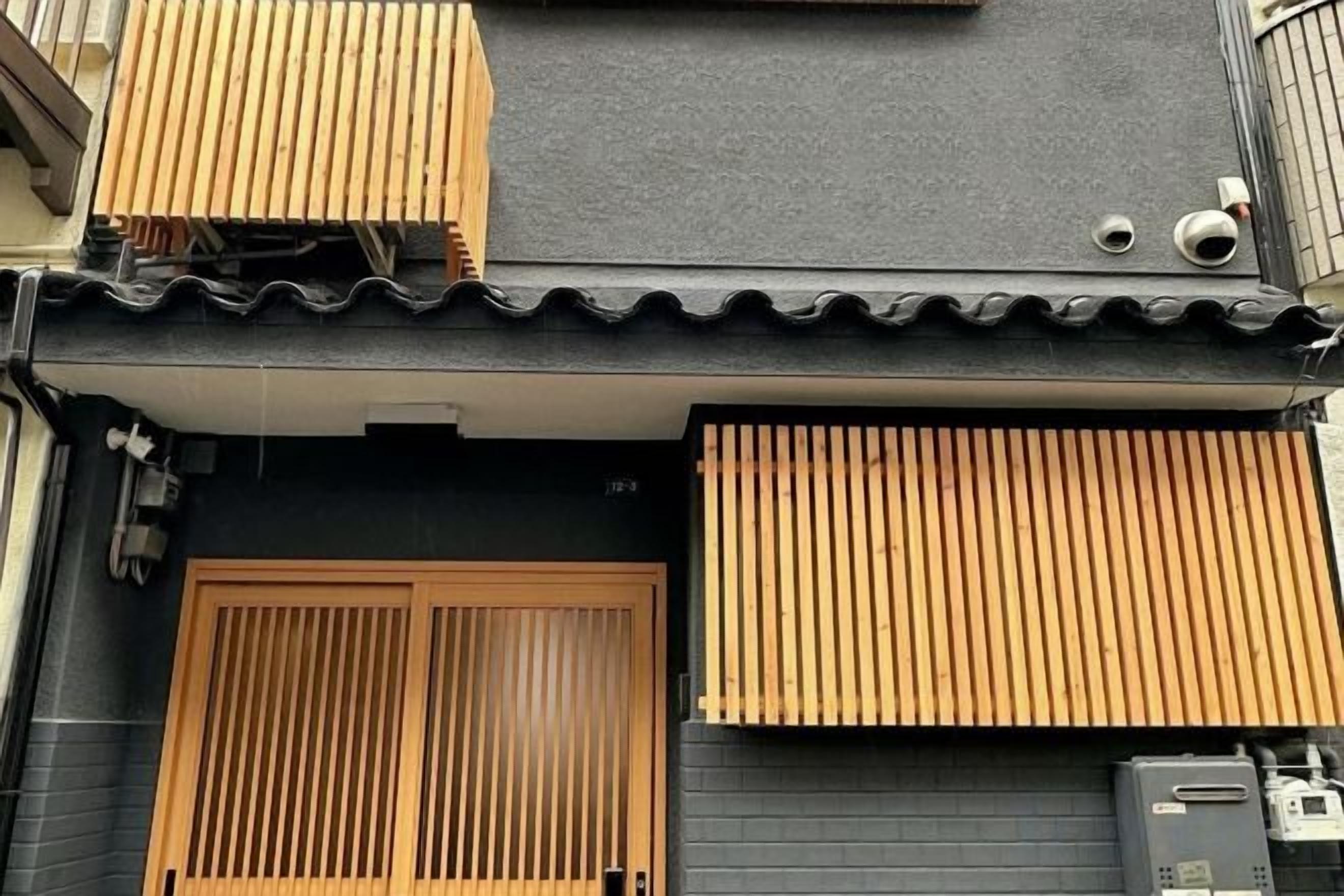 A building with a black facade, wooden sliding doors, and a tiled roof.