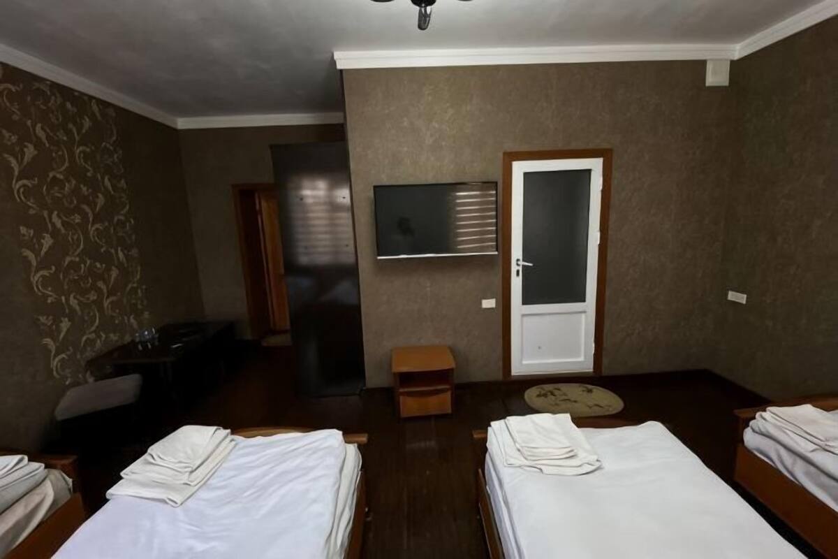 Habitación de hotel con dos camas, televisión, puerta y una mesita.