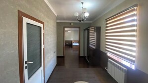 A hallway with a door, a radiator, and a window with blinds.
